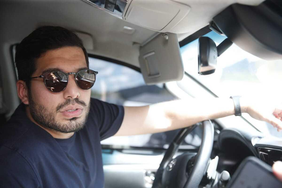 André Fernandes. Homem branco, está ao volante e usas óculos escuros