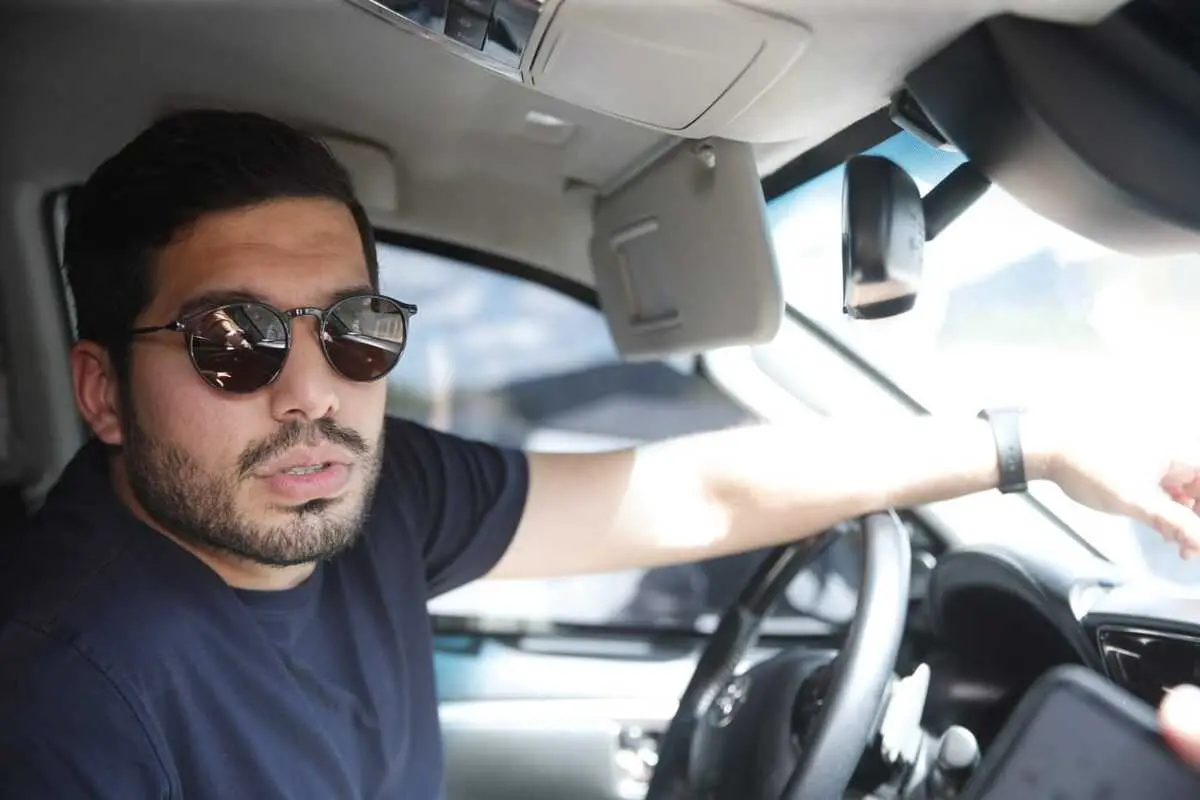 André Fernandes. Homem branco, está ao volante e usas óculos escuros
