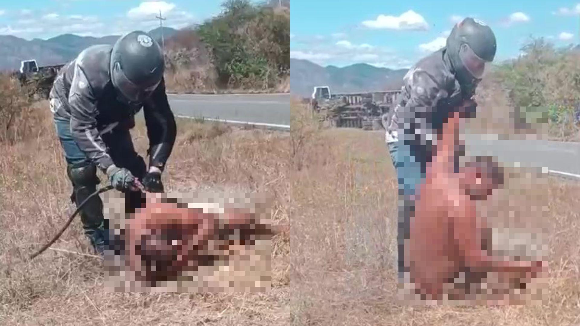 Imagem de uma ação policial em que um policial prende um homem nu no meio de uma rodovia, com vegetação e montanhas ao fundo.