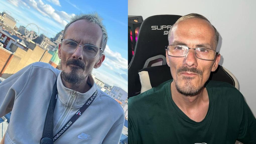 Homem de óculos com barba e cabelo grisalho, usando camiseta verde, sentado em cadeira gamer em ambiente interno, expressão séria.