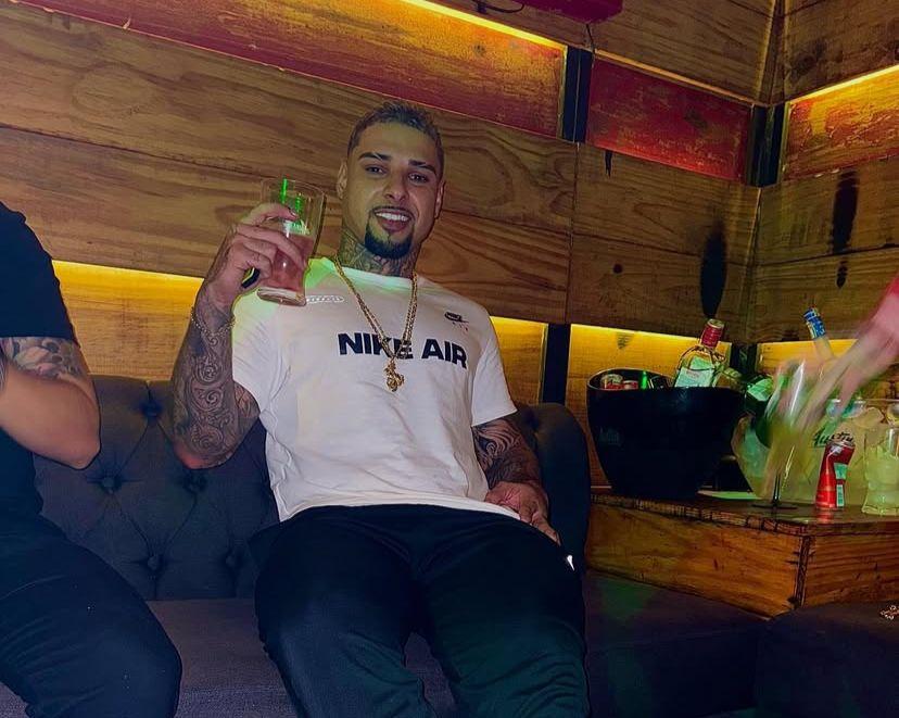 Foto de Paulo Henrique Pereira Alves, preso por integrar organização criminosa no Ceará. Ele estava com uma blusa branca, calça preta, cordão, segurando uma bebida e sentado