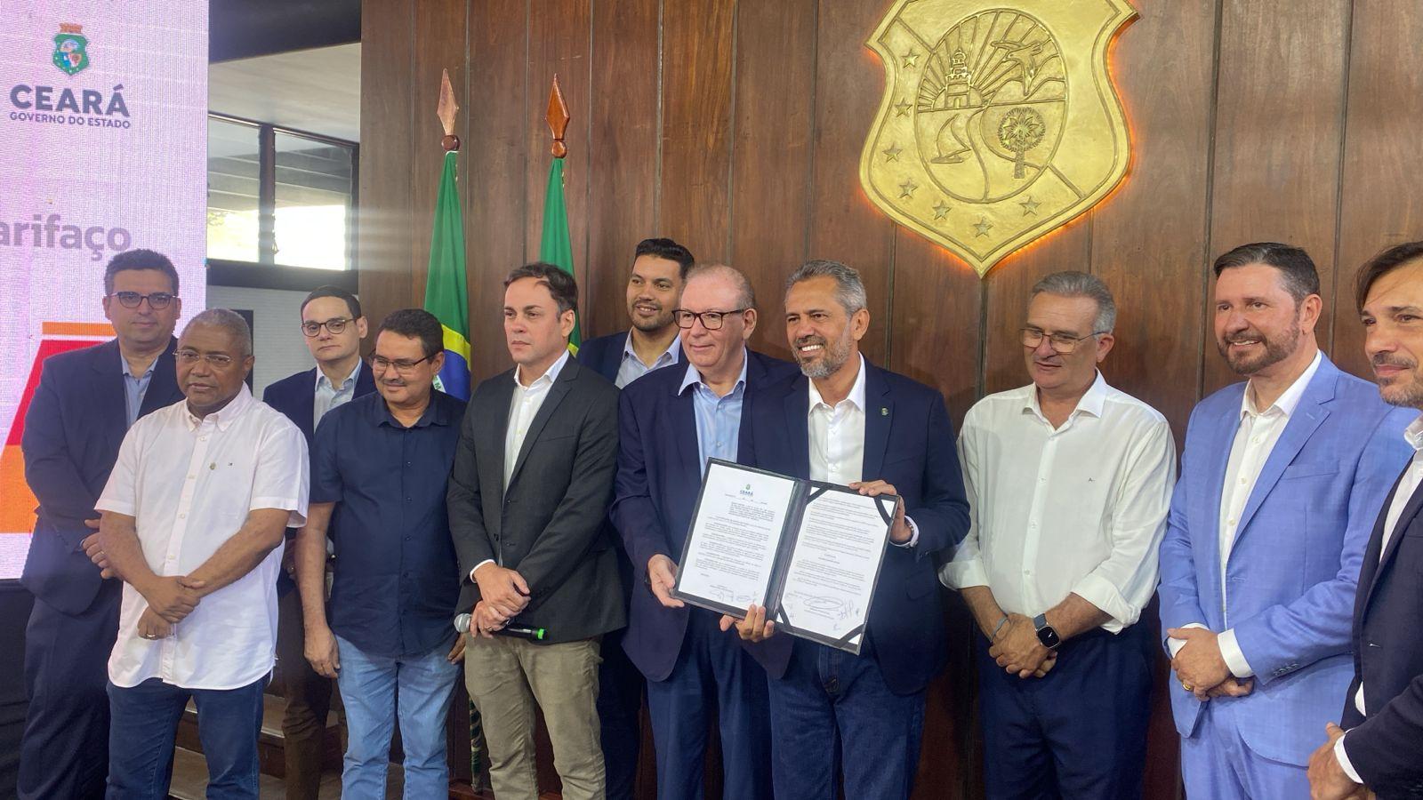 imagem mostra governador do ceará, elmano de freitas, com o decreto de socorro às empresas impactadas pelo decreto de Trump