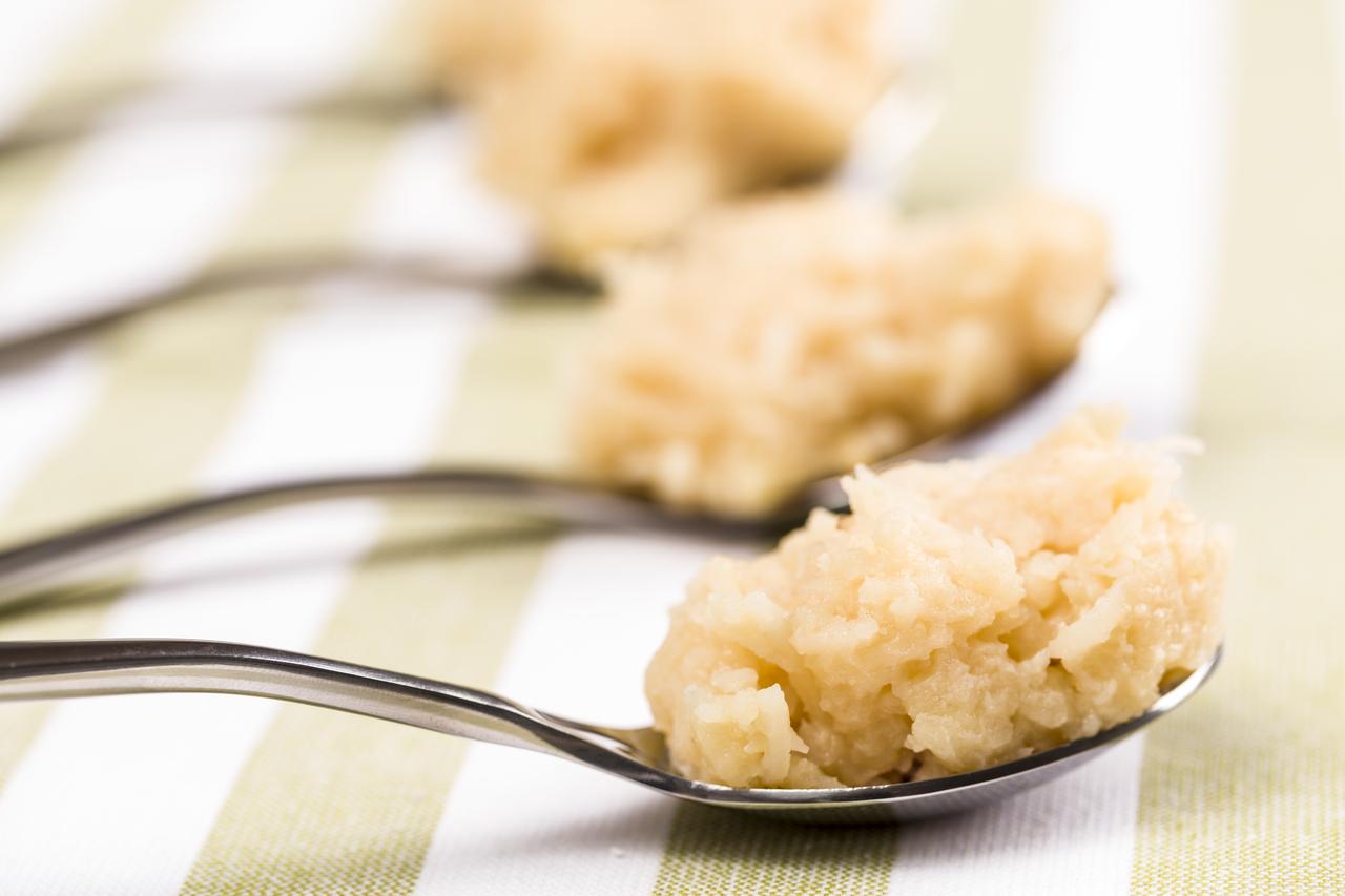 Imagem mostra fileiras de colheres com porções de cocada disposta em mesa ilustrando receita de cocada fit sem açúcar