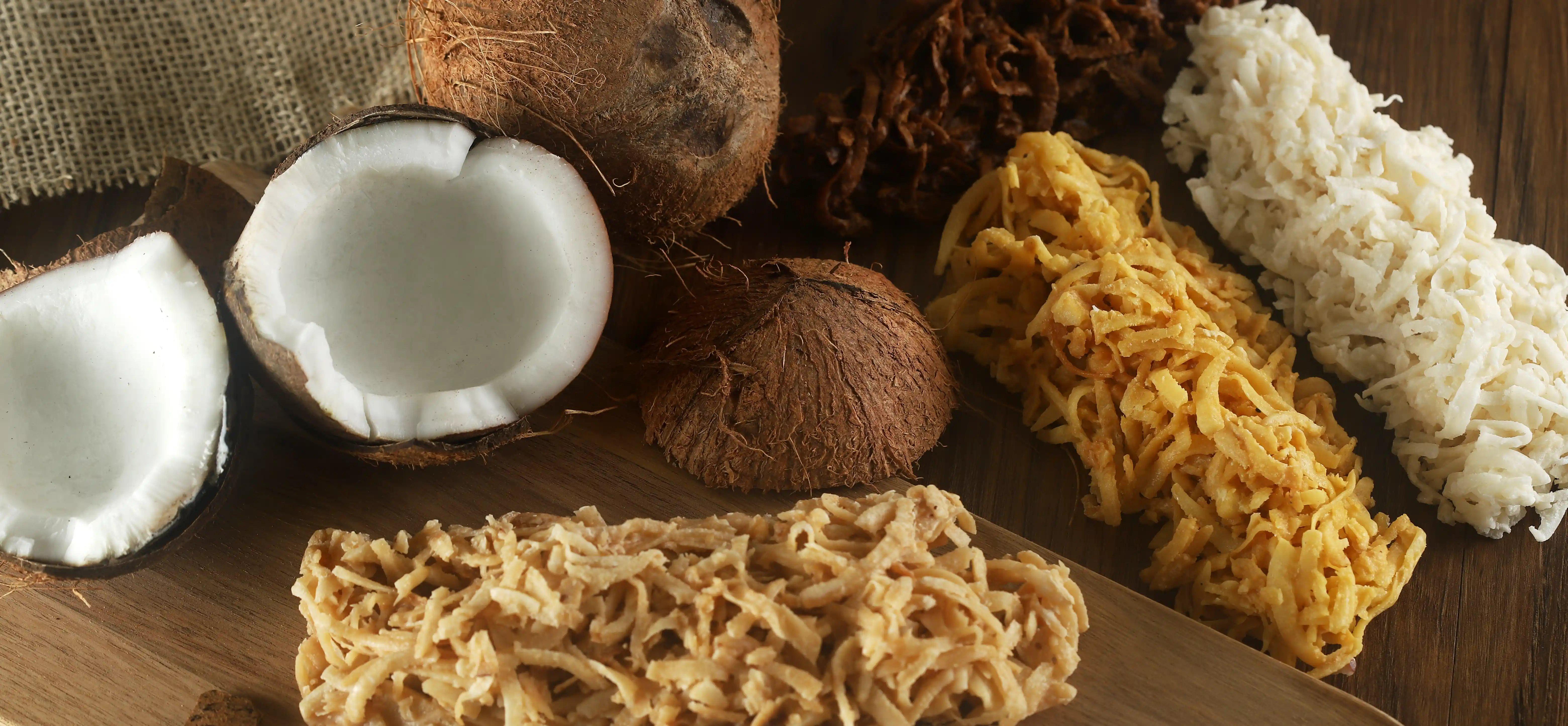Cocada caseira disposta sobre uma tábua de madeira, com coco ralado ao redor, em composição rústica e artesanal