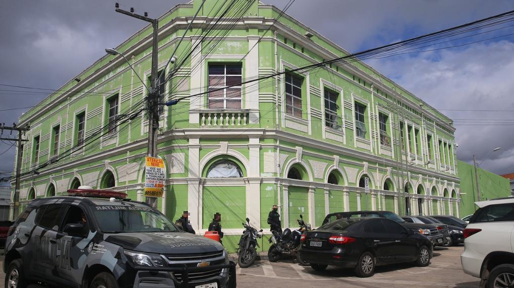Foto de fachada da Controladoria Geral de Disciplina dos Órgãos de Segurança Pública e Sistema Penitenciário do Ceará, em Fortaleza. É um prédio verde e há carros e motos estacionados em volta do edifício