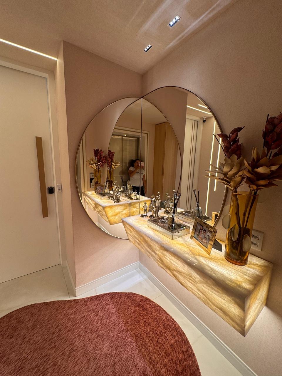 Tapete orgânico, espelho redondo e aparado em pedra iluminado marcam projeto de Hall de Entrada