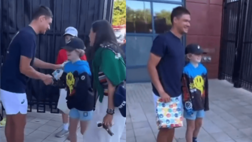 Dois momentos do reencontro entre o tenista Kamil Majchrzak e o garoto Brock, que teve o boné autografado retirado por um espectador durante o US Open. À esquerda, Majchrzak entrega presentes ao menino, que veste boné preto, moletom colorido com estampa de smiley e bermuda jeans clara, enquanto uma mulher observa a cena sorrindo. À direita, o tenista e o garoto posam juntos para uma foto, ambos sorrindo, em frente a um prédio com janelas de vidro.