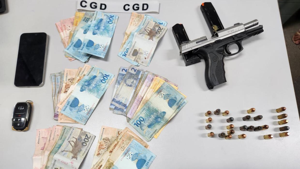 Imagem mostra uma arma de fogo, munições e dinheiro apreendidos com um policial militar, em Canindé, em uma operação em fevereiro de 2024