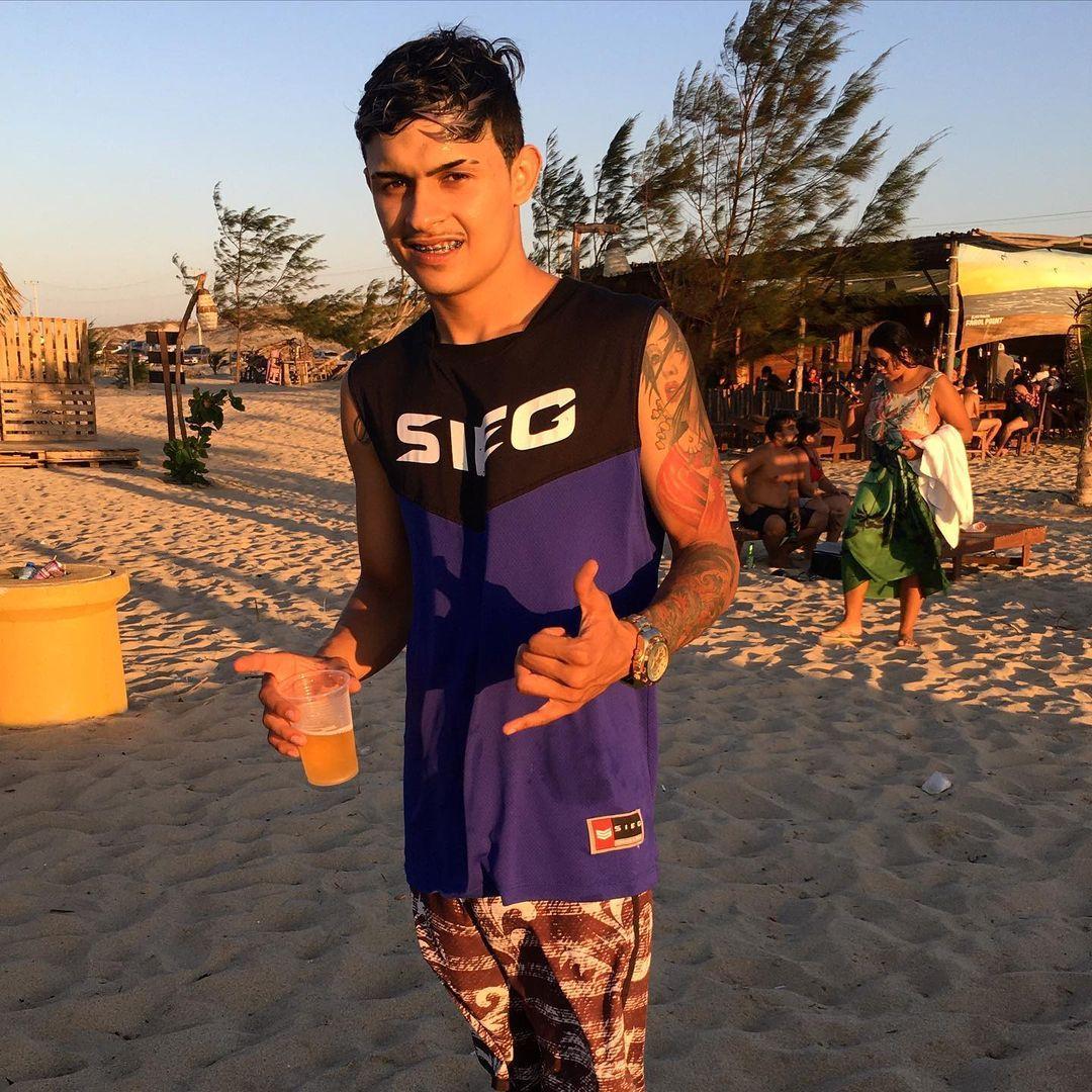 Foto do jovem Mateus Silva Cruz, assassinado a tiros aos 19 anos, dentro da Delegacia Regional de Camocim, em fevereiro de 2022. Na imagem, ele está na praia, veste uma blusa roxa e preta, sem mangas