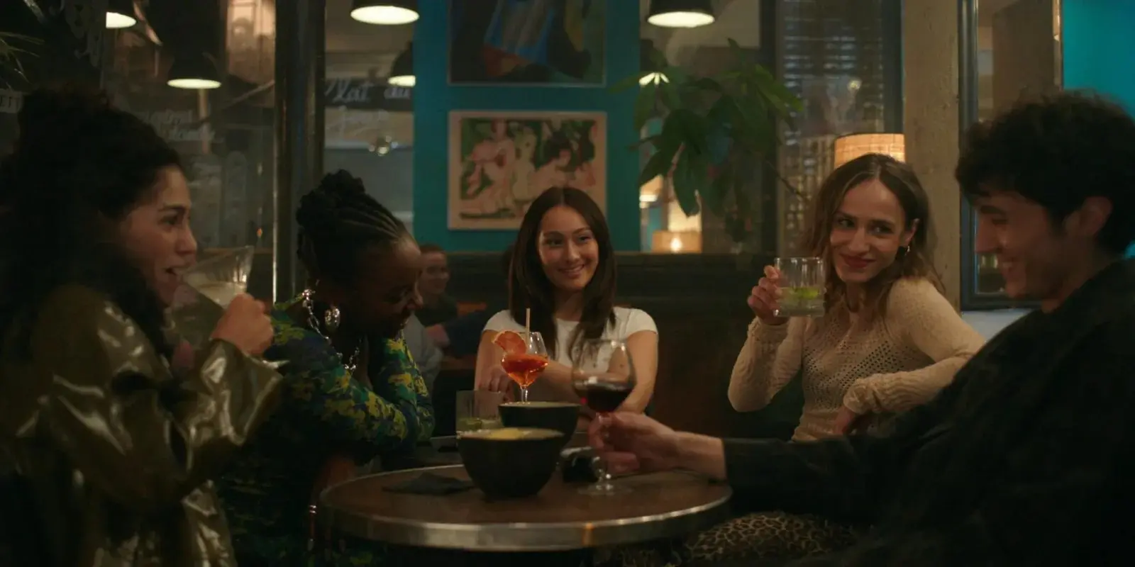 Cena de O Verão Que Mudou a Minha Vida, com parte dos personagens sentados à mesa, conversando e comendo