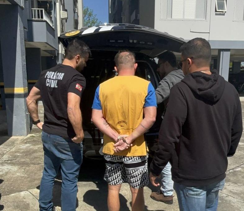 Foto mostra policiais civis realizando a prisão de Leandro Farias da Silva em um condomínio. Três policiais conduzem um homem preso e algemado