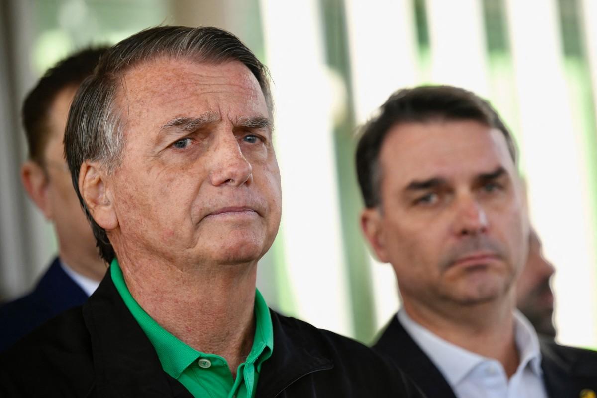 Bolsonaro durante entrevista à imprensa. Ao fundo, seu filho, o senador Flávio Bolsonaro