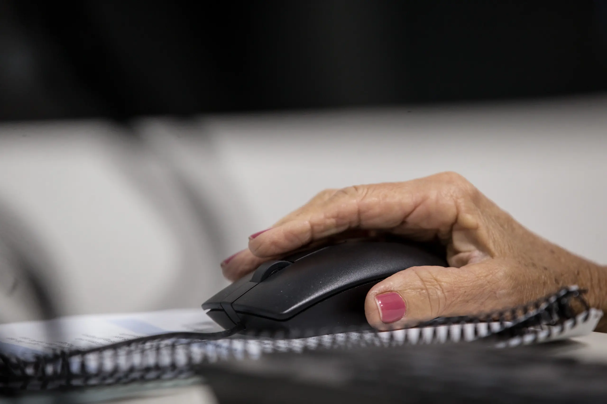 Mão de mulher idosa usando um mouse de computador.