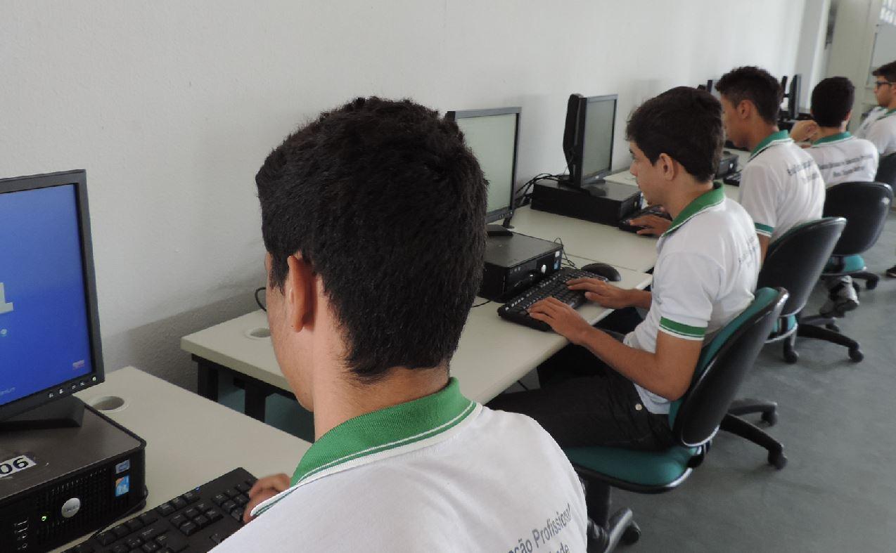 Alunos do Ensino Médio estadual utilizando computadores em laboratório de informática