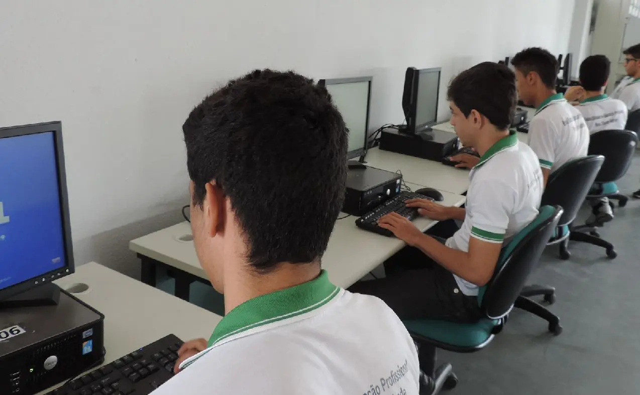Alunos do Ensino Médio estadual utilizando computadores em laboratório de informática