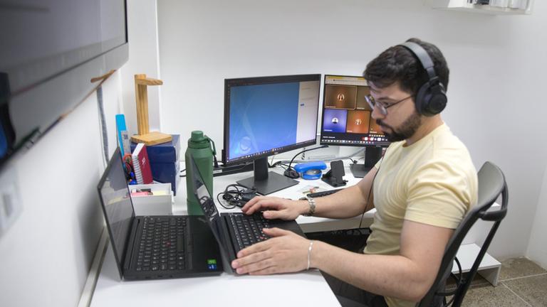 Homem de barba e headphones digita em computador na UFC