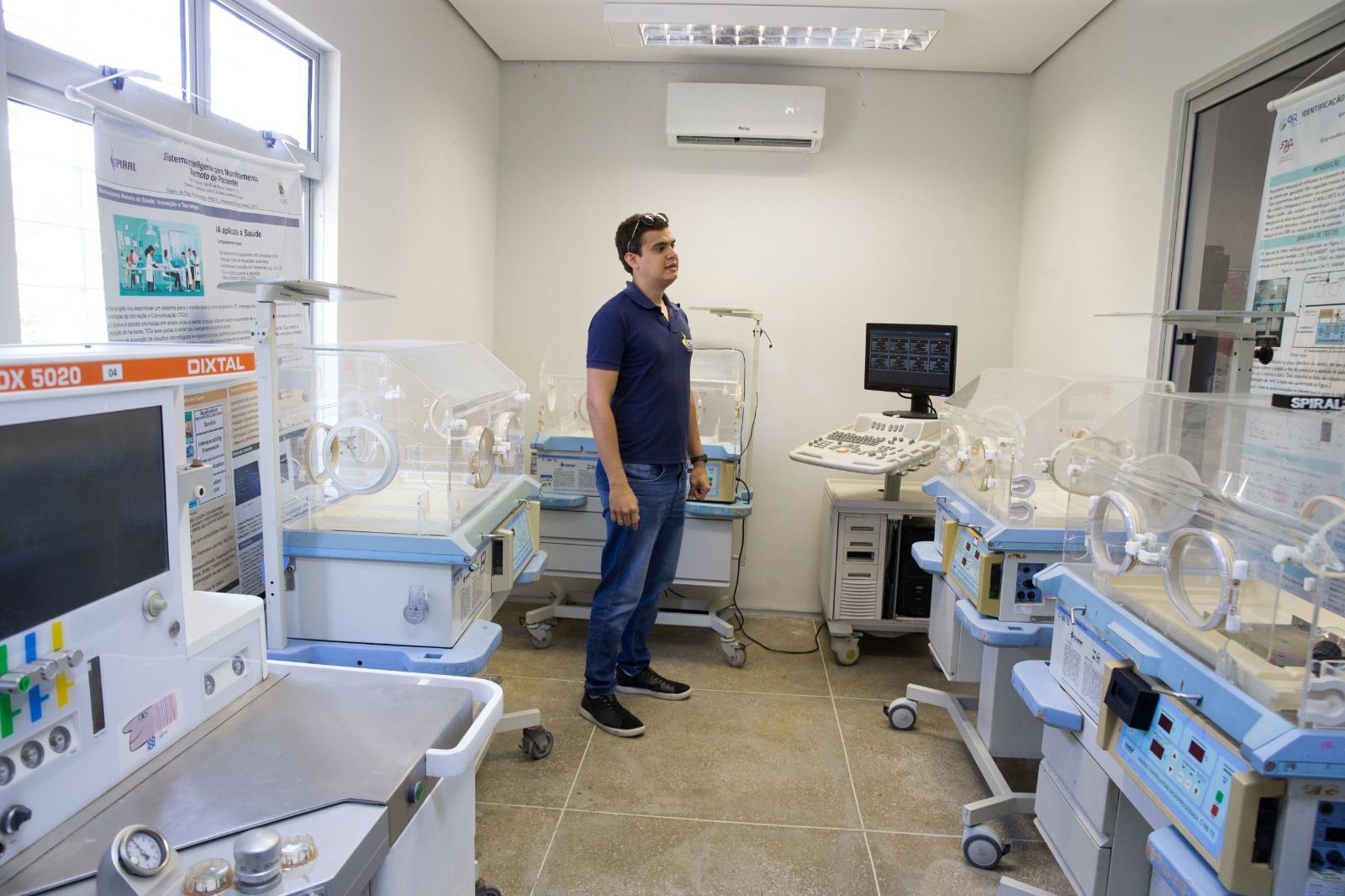 Pesquisador ao centro mostra uso de computadores para monitorar sinais de bebês em incubadoras