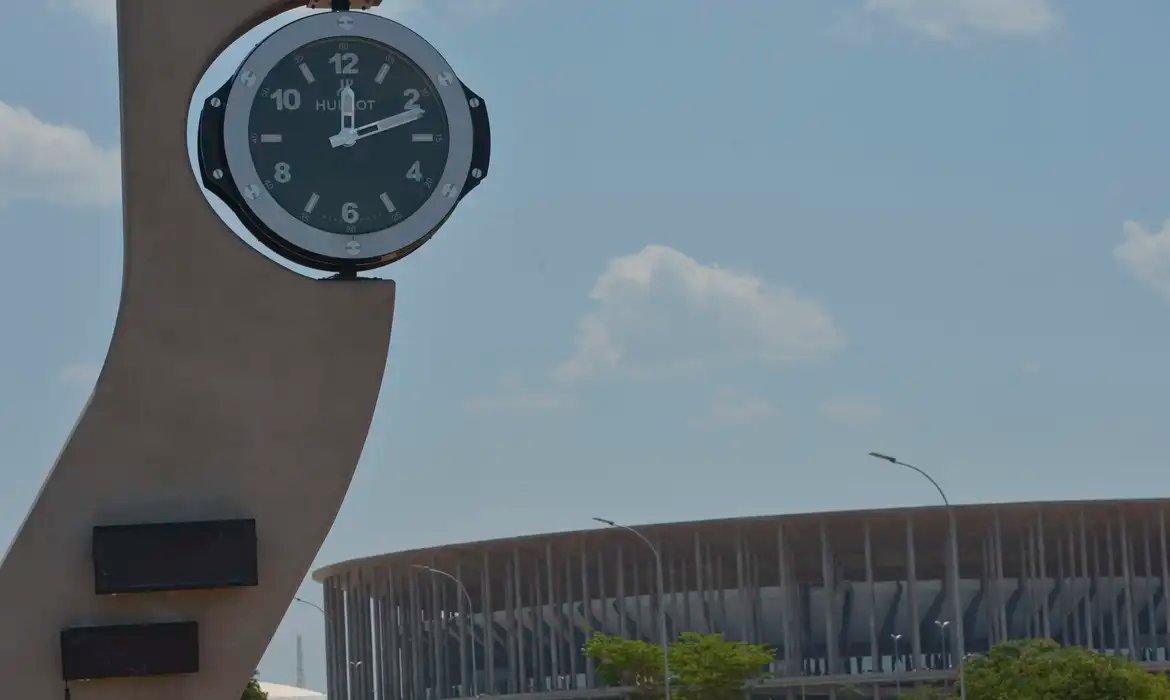 Relógio em Brasília com o estádio Mané Garrincha ao fundo