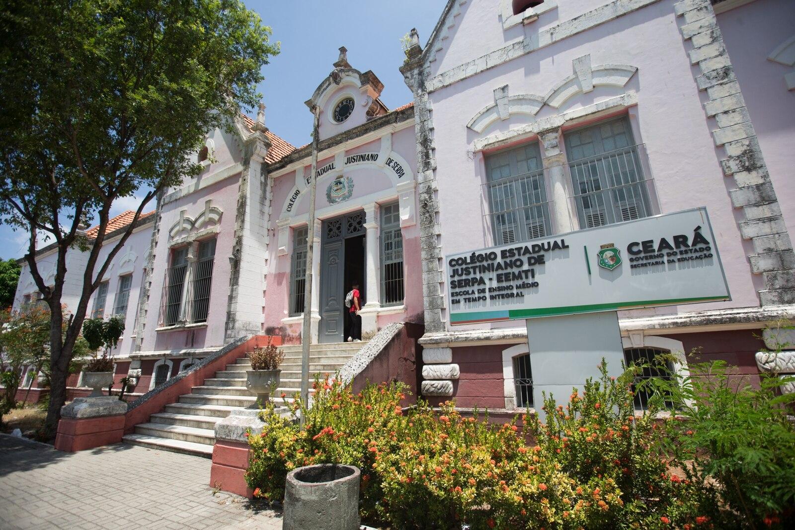 Imagem mostra fachada do colégio Justiniano de Serpa, um dos mais antigos do Ceará. A construção tem traços antigos, em tons de rosa, e uma escadaria no centro dando acesso ao prédio.
