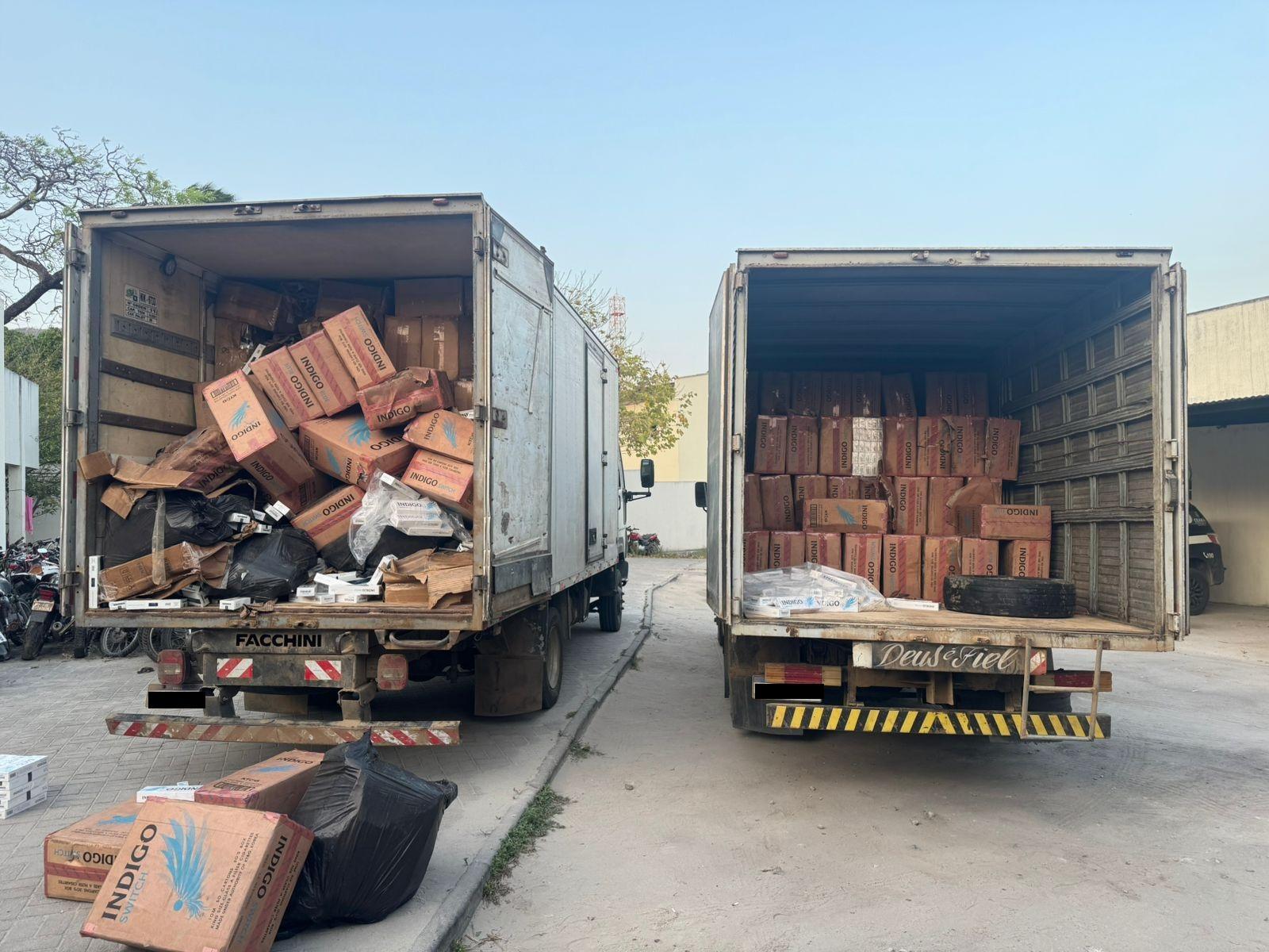 Caminhões de transporte de cargas com caixas de cigarros contrabandeados empilhadas em baús dos veículos apreendidos pela Polícia Militar em Amontada.