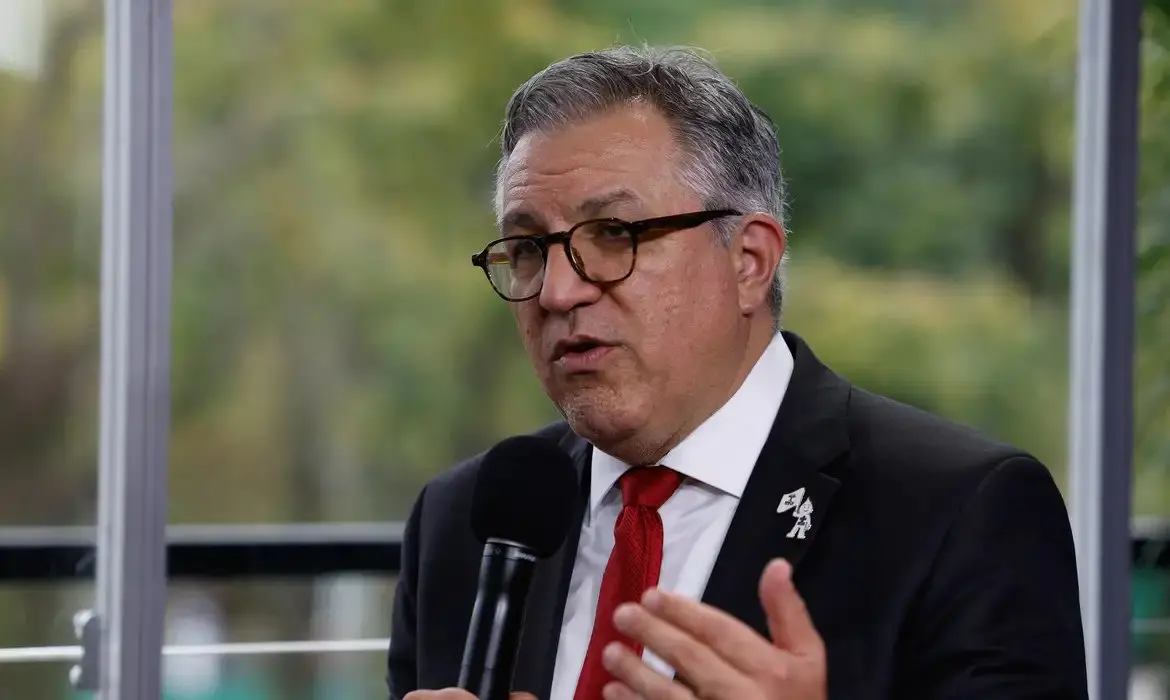 Alexandre Padrilha, ministro da Saúde, fala ao microfone. Ele usa um terno preto com gravata vermelha.