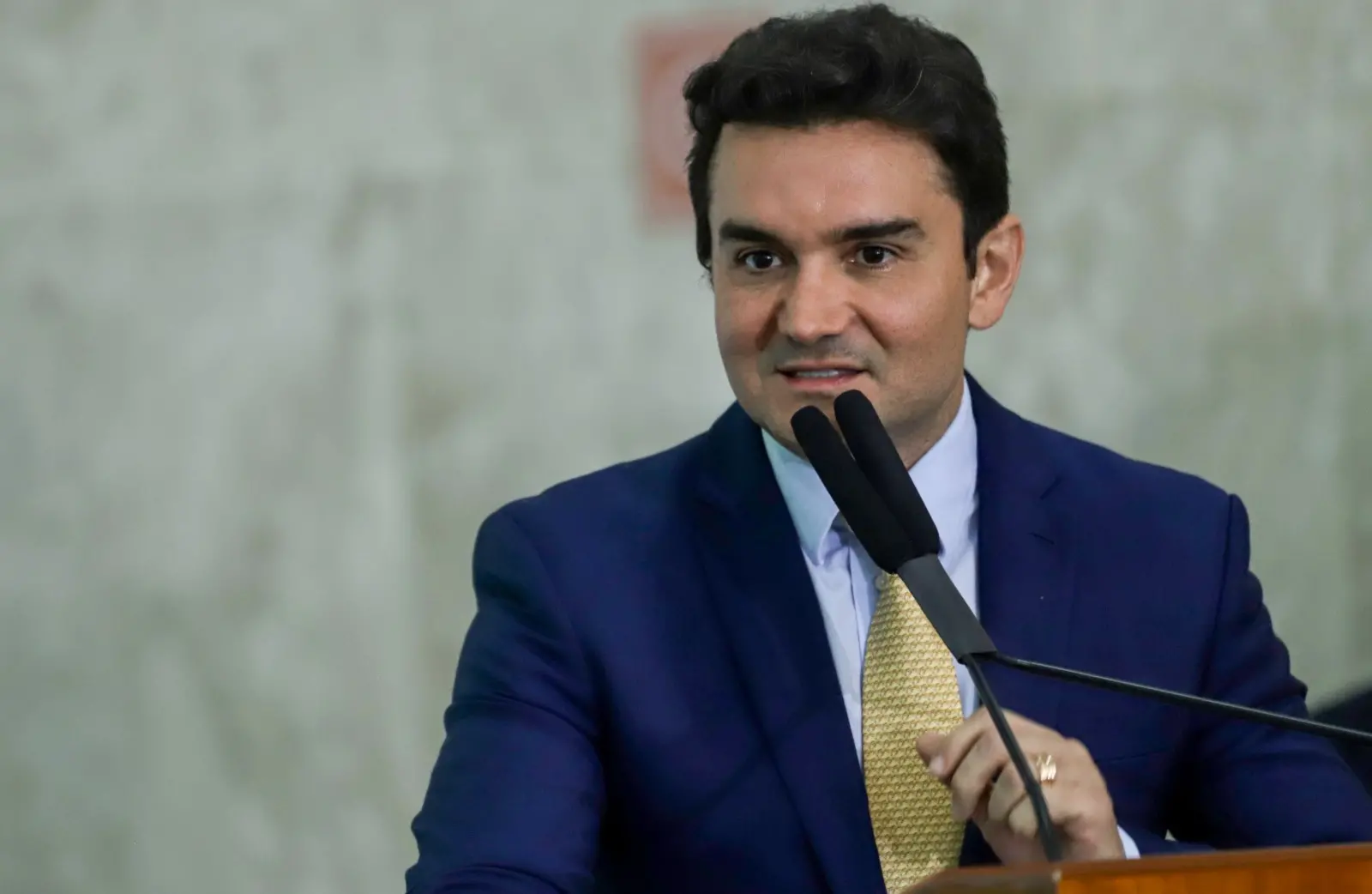 Celso Sabino é um homem de meia idade, branco e de cabelo preto, que usa terno azul, camisa social branca e gravata amarela.