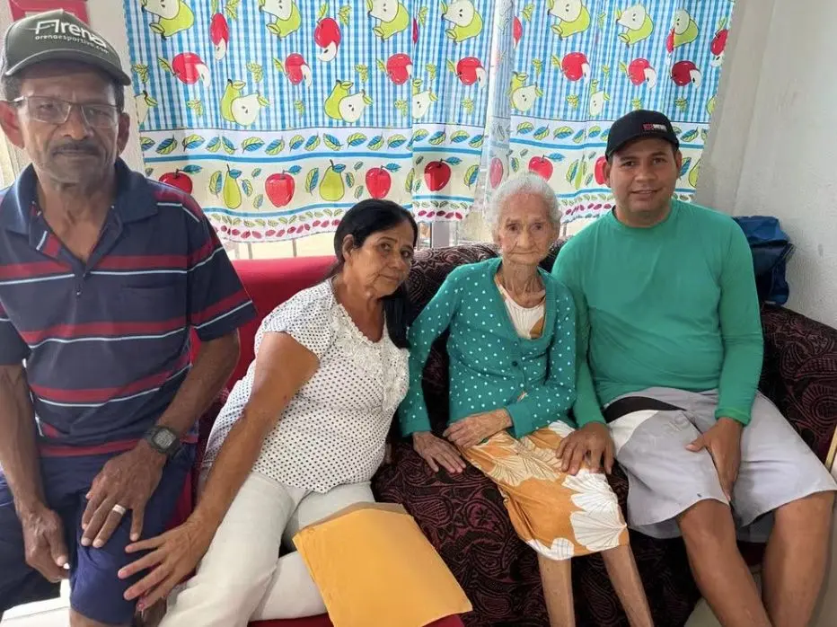 Dona Joana, com blusa verde e de bolinhas e rodeada da família, tem 116 anos