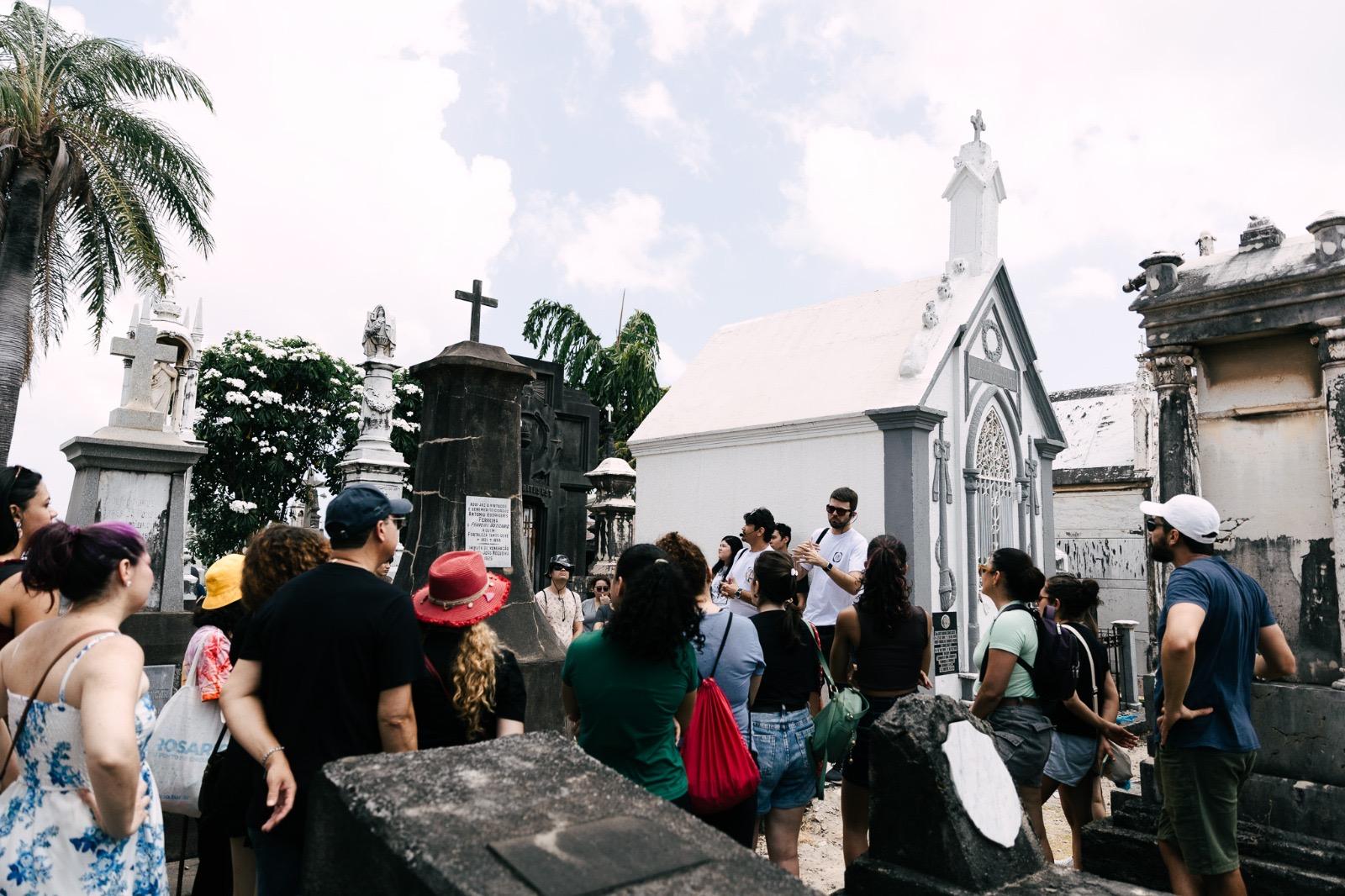 Um grupo de pessoas acompanha os professores Sandoval Matoso e Thiago Roque em visita ao Cemitério São João Batista