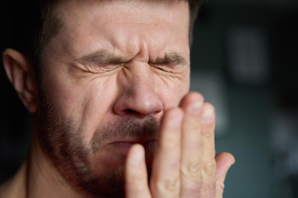 Foto de homem sentindo o próprio mau hálito. Imagem para ilustrar matéria sobre halitose.
