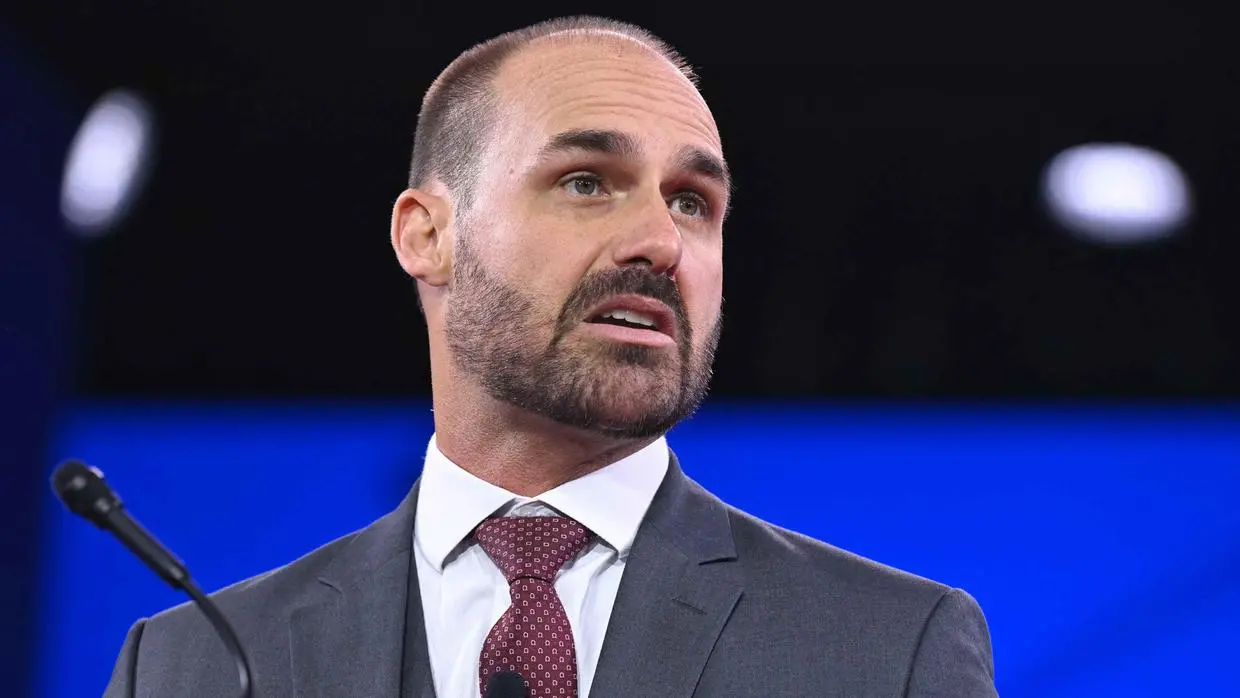 Eduardo Bolsonaro está ao lado de um microfone