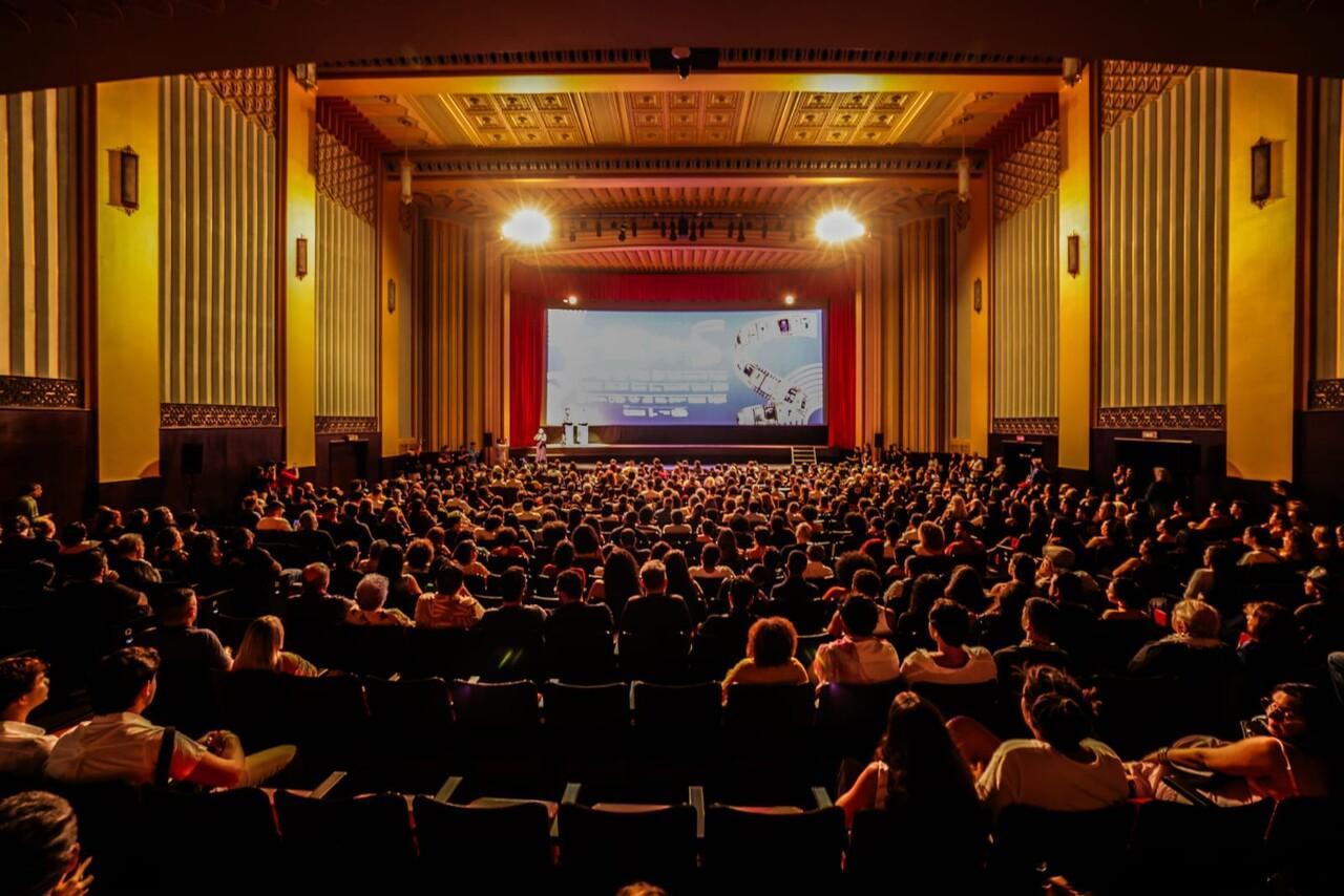 Imagem da sala de exibições do cineteatro São Luiz, em Fortaleza, com plateia lotada assistindo apresentação na tela