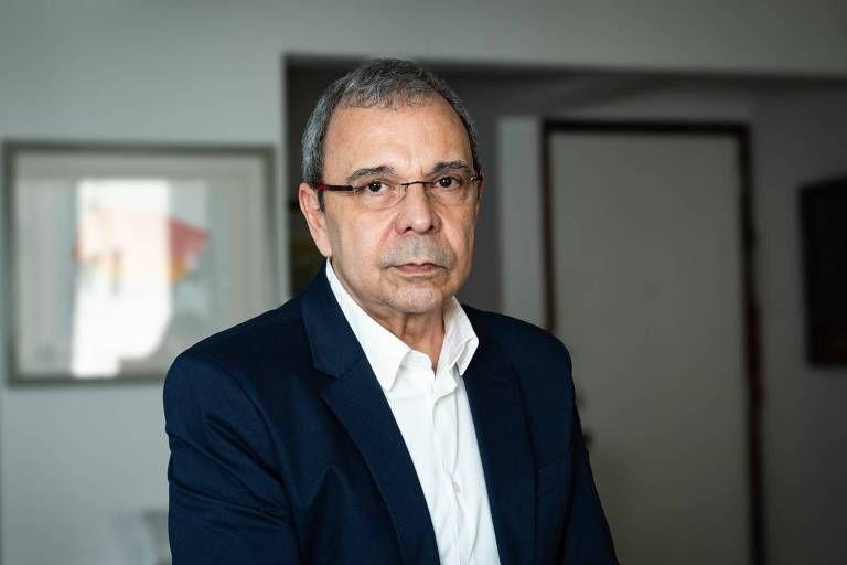 Historiador e professor da UFRJ, Carlos Fico. Ele usa óculos, camisa branca e blazer azul escuro, olhando sério para a câmera em ambiente interno.