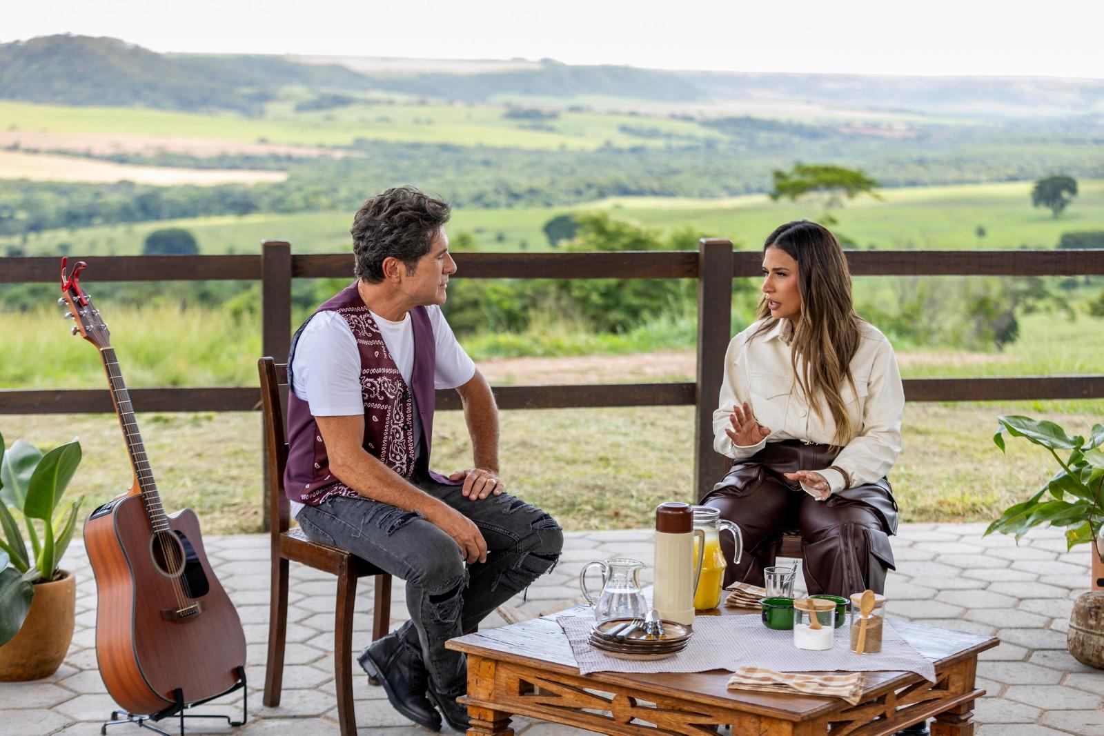 Daniel e Simone conversam com uma vista de pastagem ao fundo.