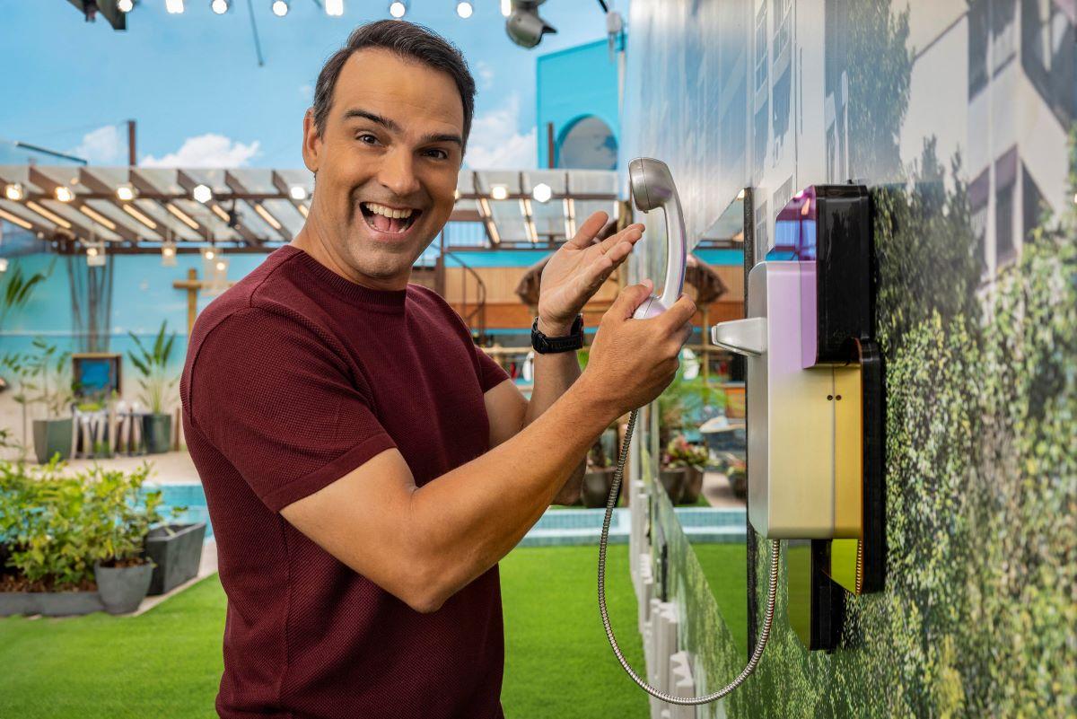 Foto do apresentador do BBB, Tadeu Schmidt, segurando o Big Fone, na casa do reality show