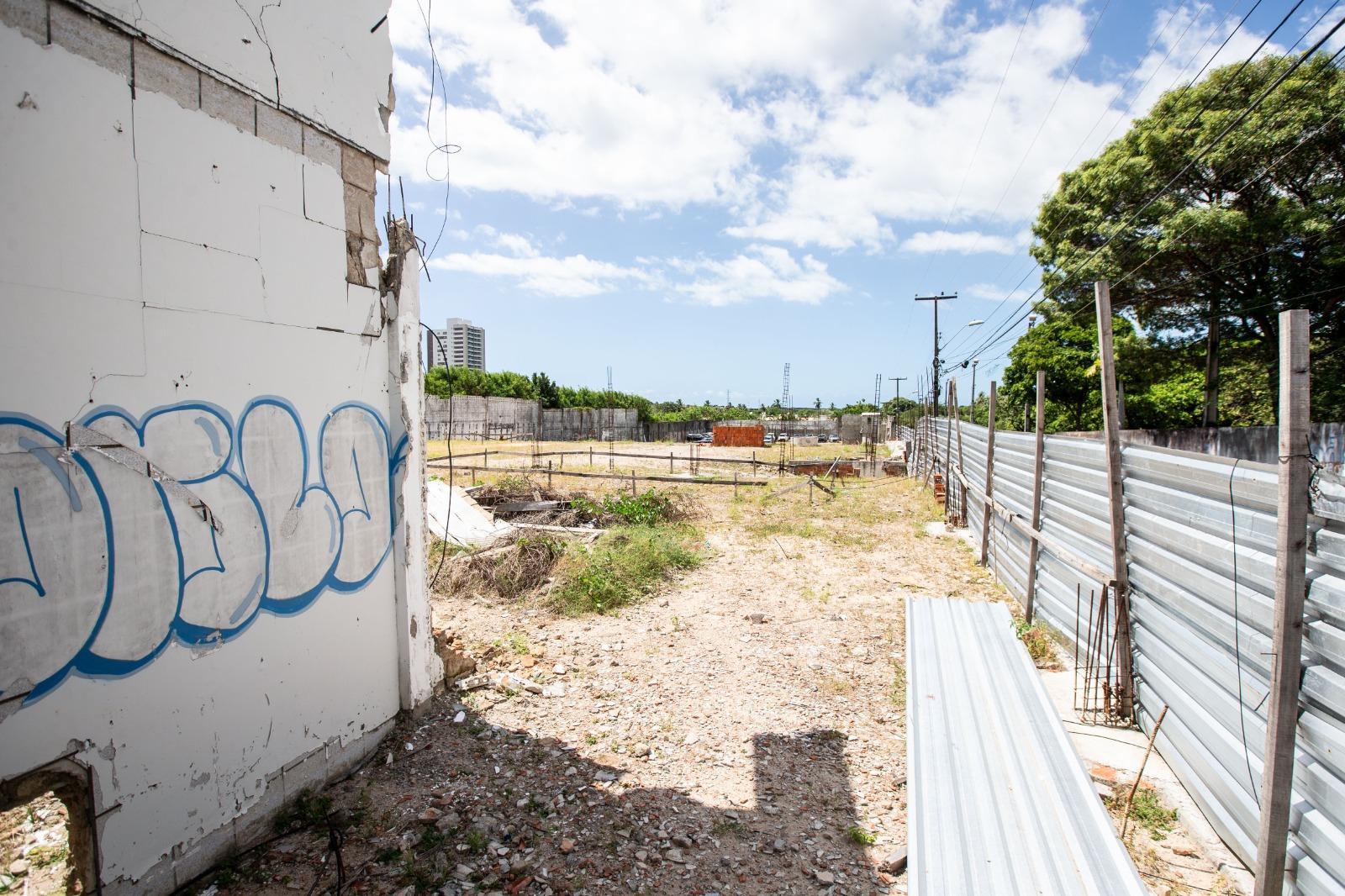 Imagem de terreno vazio, cercado por tapumes metálicos