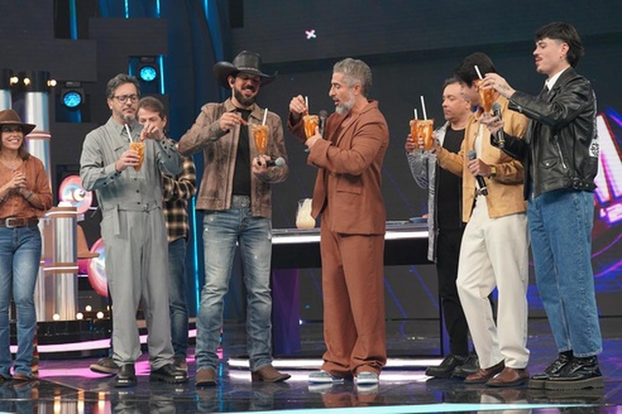 Celebridades brasileiras comemorando em evento ao lado de outras pessoas, todos segurando copos com drinks em um ambiente de palco bem iluminado. No programa Caldeirão do Mion