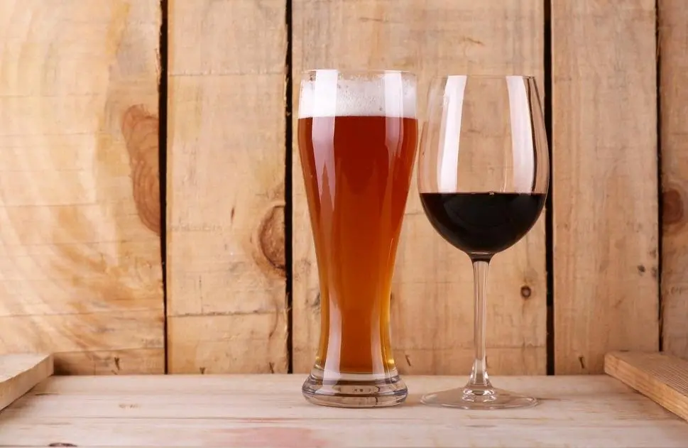 Copo de cerveja ao lado de uma taça de vinho. Imagem usada em matéria sobre intoxicação por metanol.