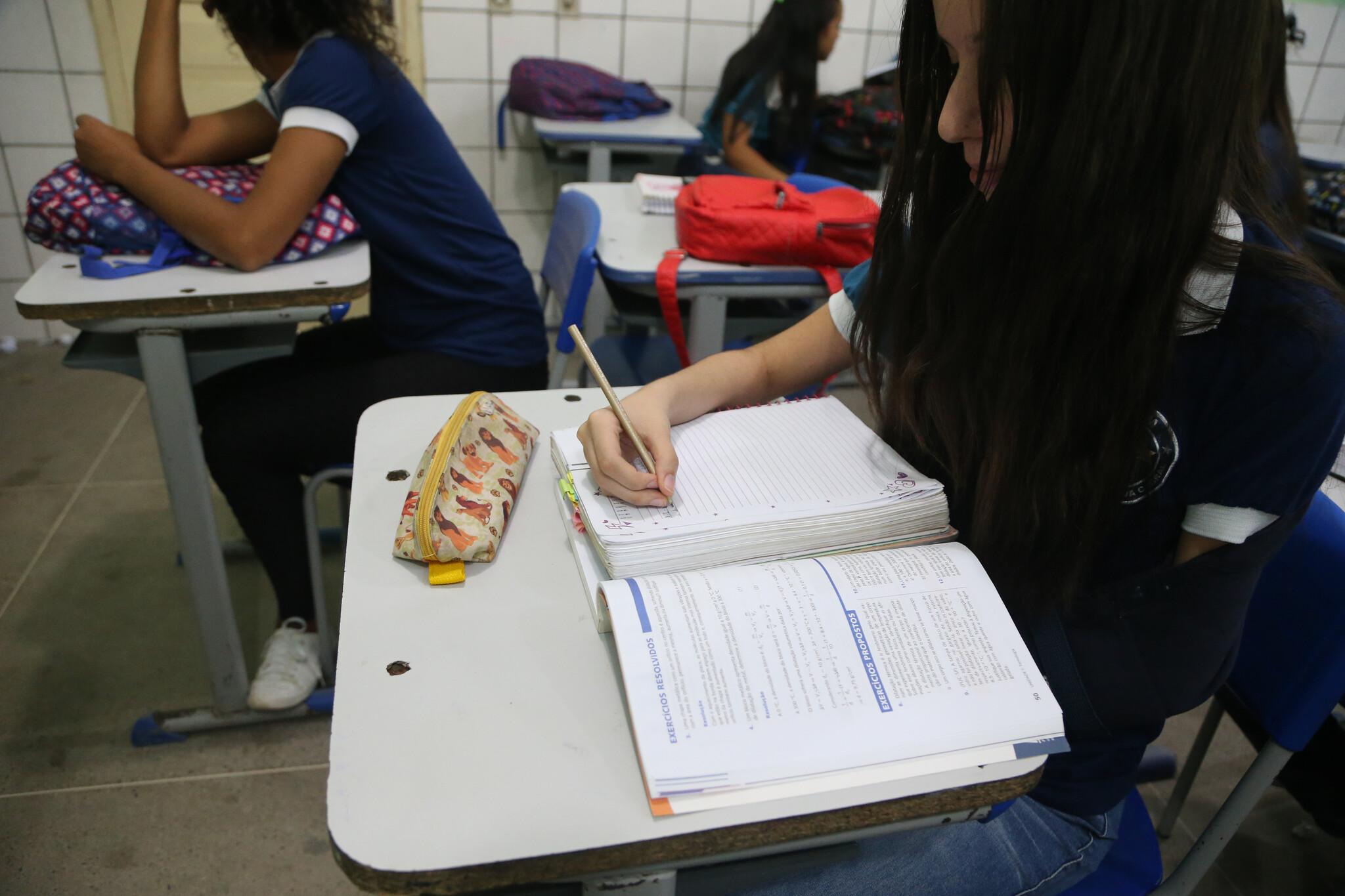 Aluna escrevendo em caderno durante a aula.