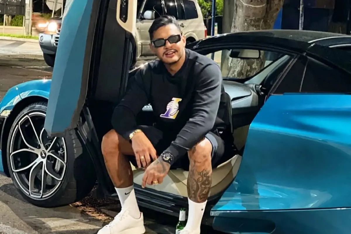 Imagem do cantor Hungria sentado em um carro com a porta aberta.