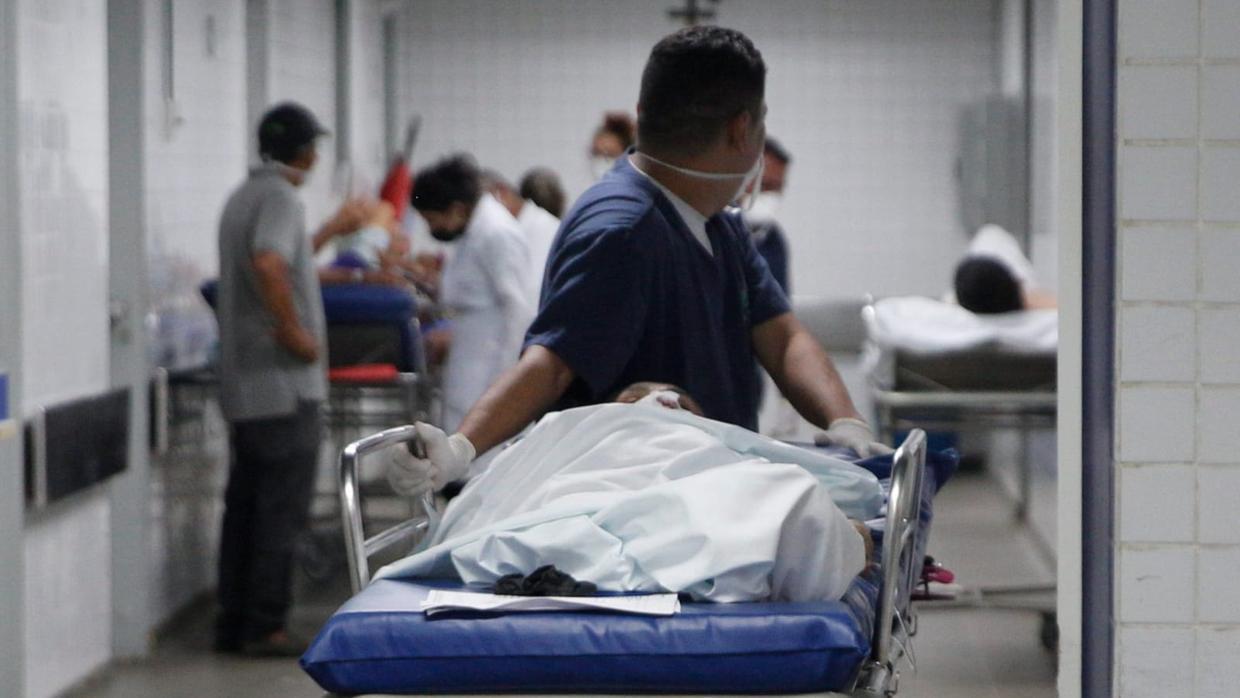 homem carrega maca com paciente dentro de hospital