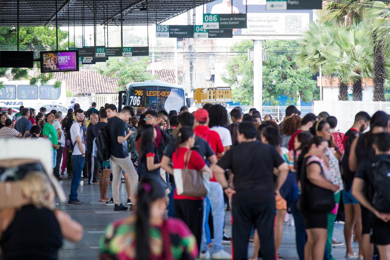 Pessoas esperando ônibus chegar em terminal de Fortaleza.