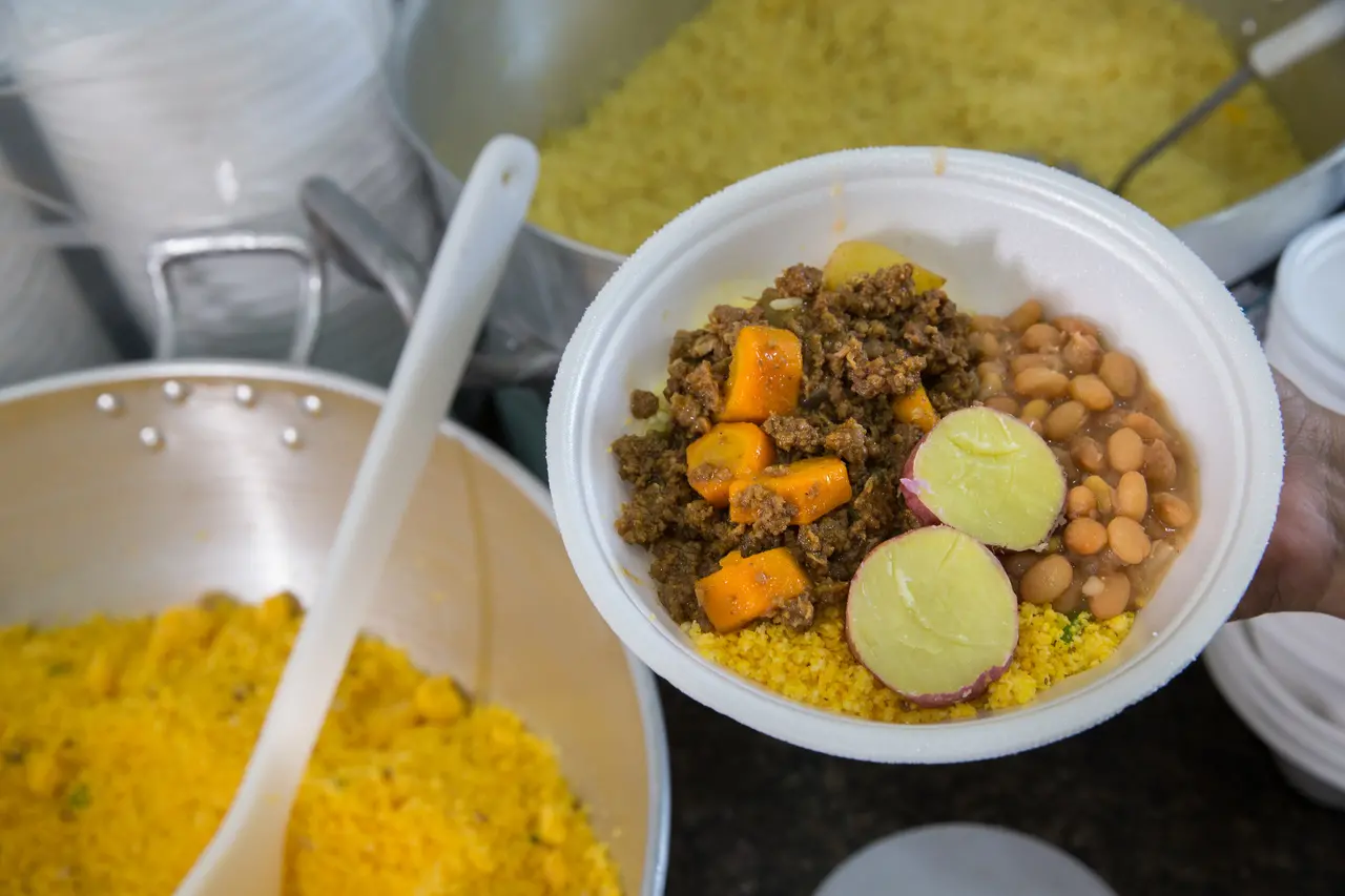 Quentinha com arroz, feijão, carne, batata doce e farofa.