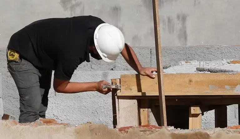 Imagem mostra homem trabalhando em construção de casa