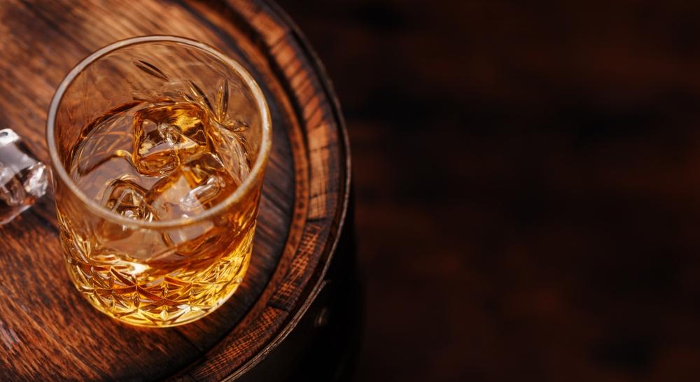 Copo de uísque sobre barril de madeira.
