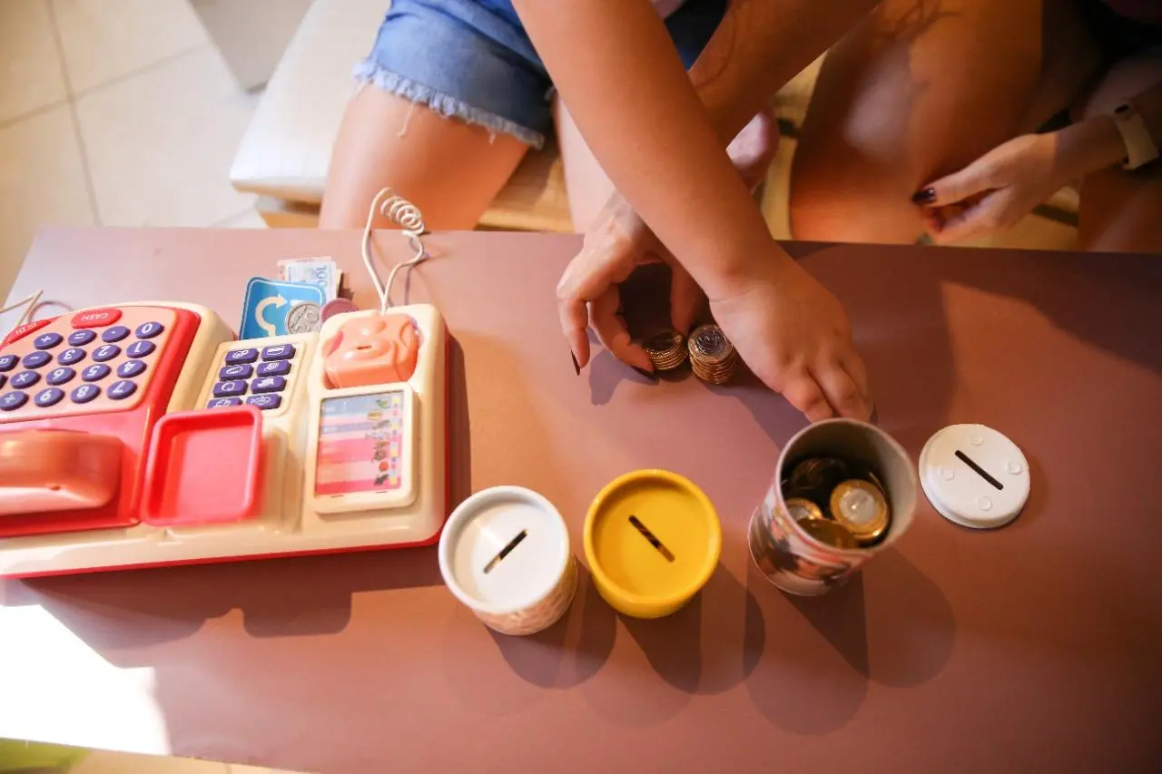 Foto mostra criança brincando com os cofrinhos.