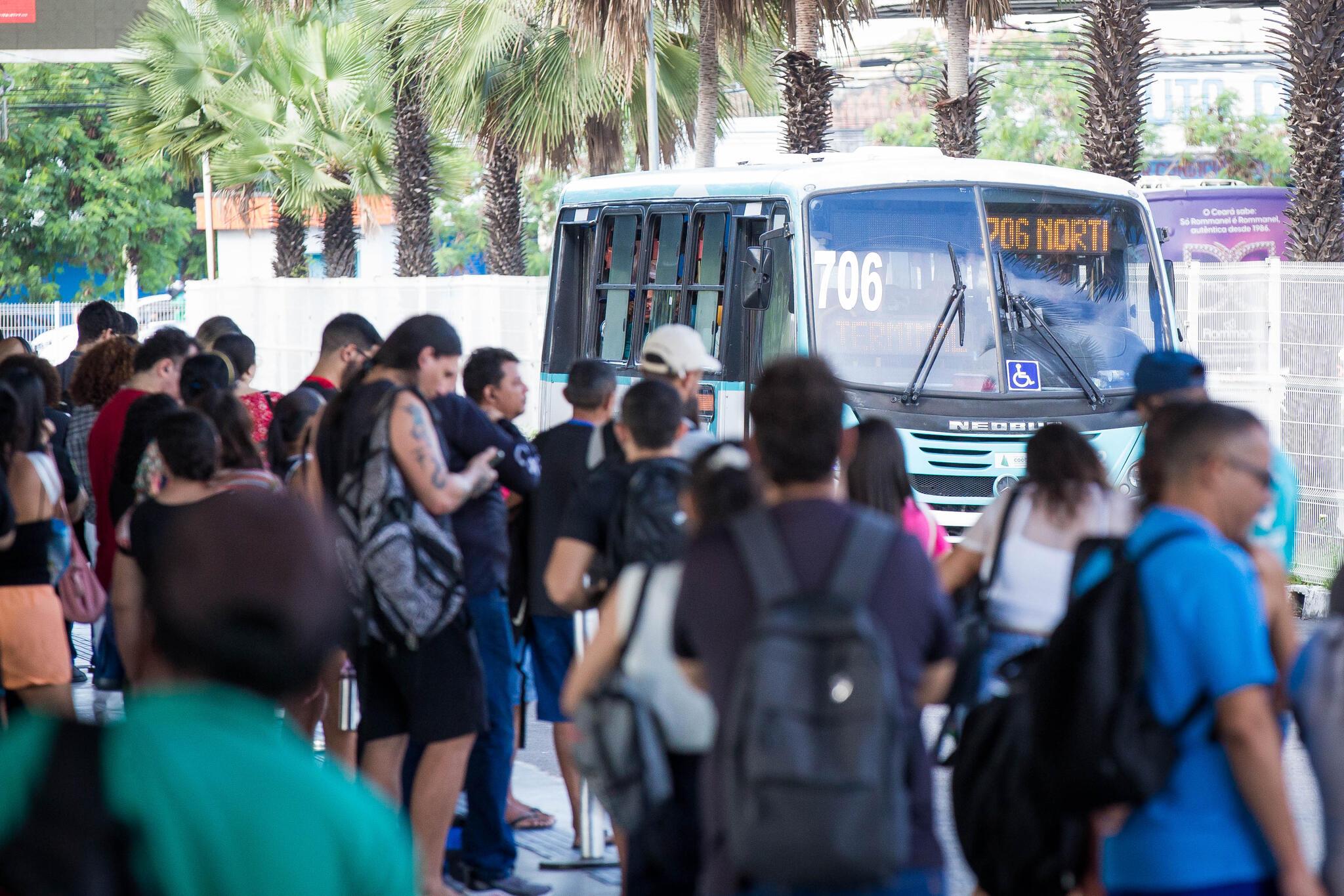 Pessoas aguardando ônibus em terminal.