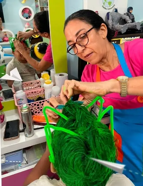 Mulher arruma cabelo de menino em formato de iguana.