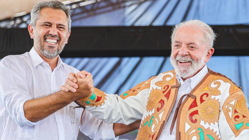 Lula e Elmano lado a lado em cima de um palco. Lula veste uma peça cearense de Espedito Seleiro