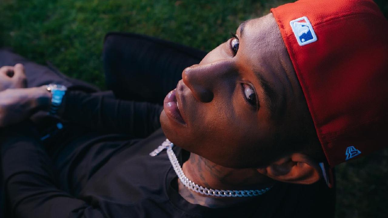 Cantor Spark olhando para cima em direção ao fotógrafo. Ele usa boné