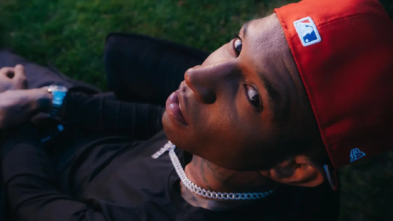 Cantor Spark olhando para cima em direção ao fotógrafo. Ele usa boné